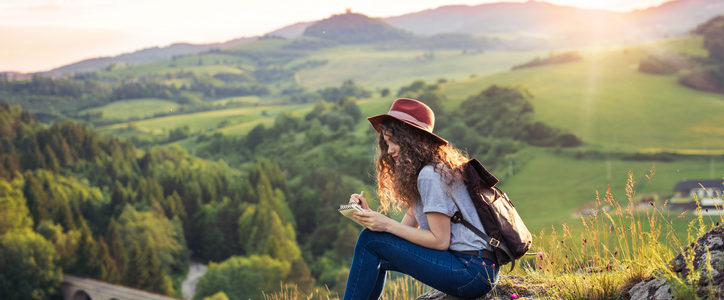 woman hiker taking notes on a hillside