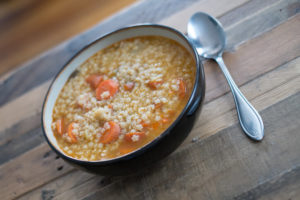 bowl of chicken and stars soup on table with spoon