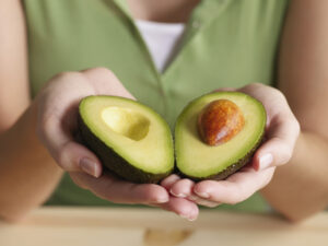 Woman holding halved avocado