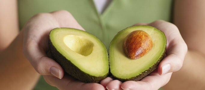 Woman holding halved avocado