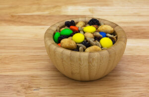 Sweet and salty trail mix in a wood bowl isolated on a countertop side view.