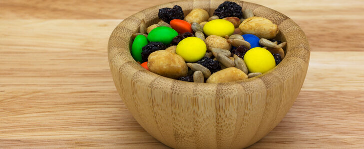 Sweet and salty trail mix in a wood bowl isolated on a countertop side view.