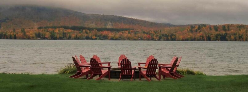 adirondack chairs in a circle in front of a lake