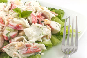 Mayonnaise seafood salad with shrimp and crab meat and fresh dill, romaine lettuce, and basil leaf garnish